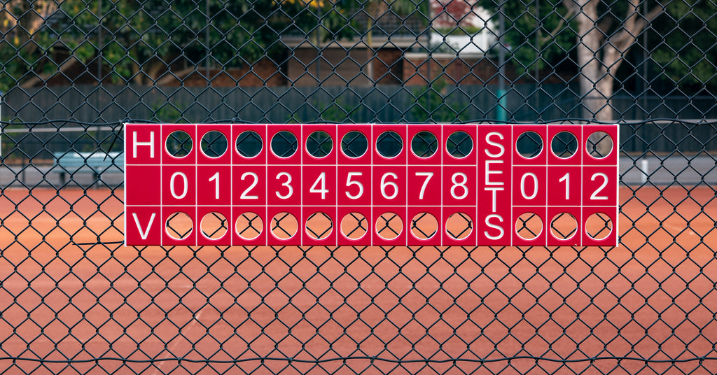 Tennis scoreboard on a chain-link fence with a tennis court background